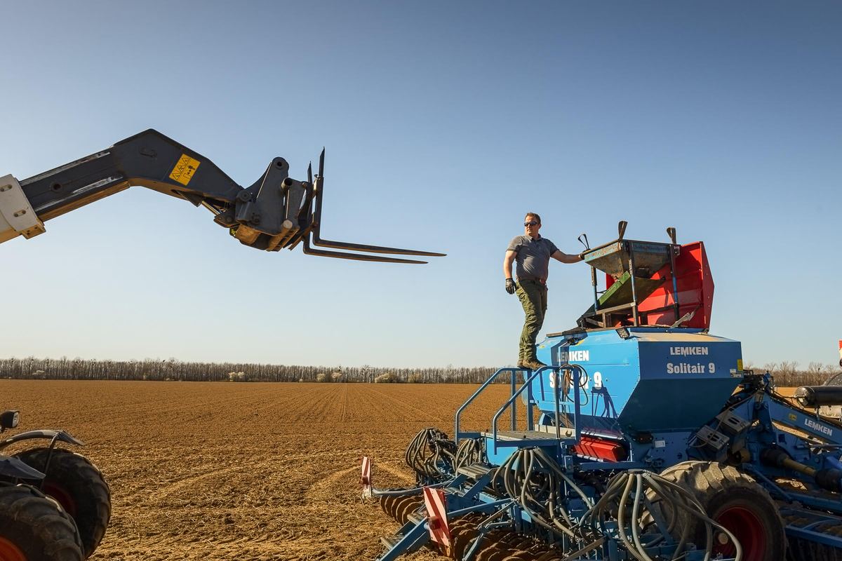 Agriculteur debout sur son semoir en plein champ